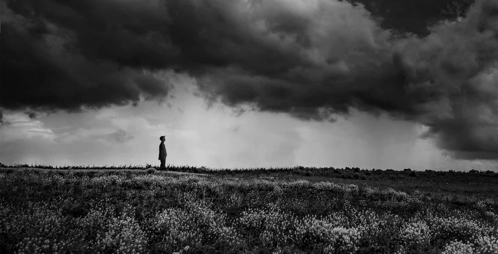 photo of man standing under storm clouds